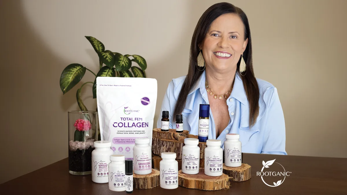 Isa Herrera smiling at a wood table with a Total Fem Collagen pouch and white supplement bottles on wood risers.